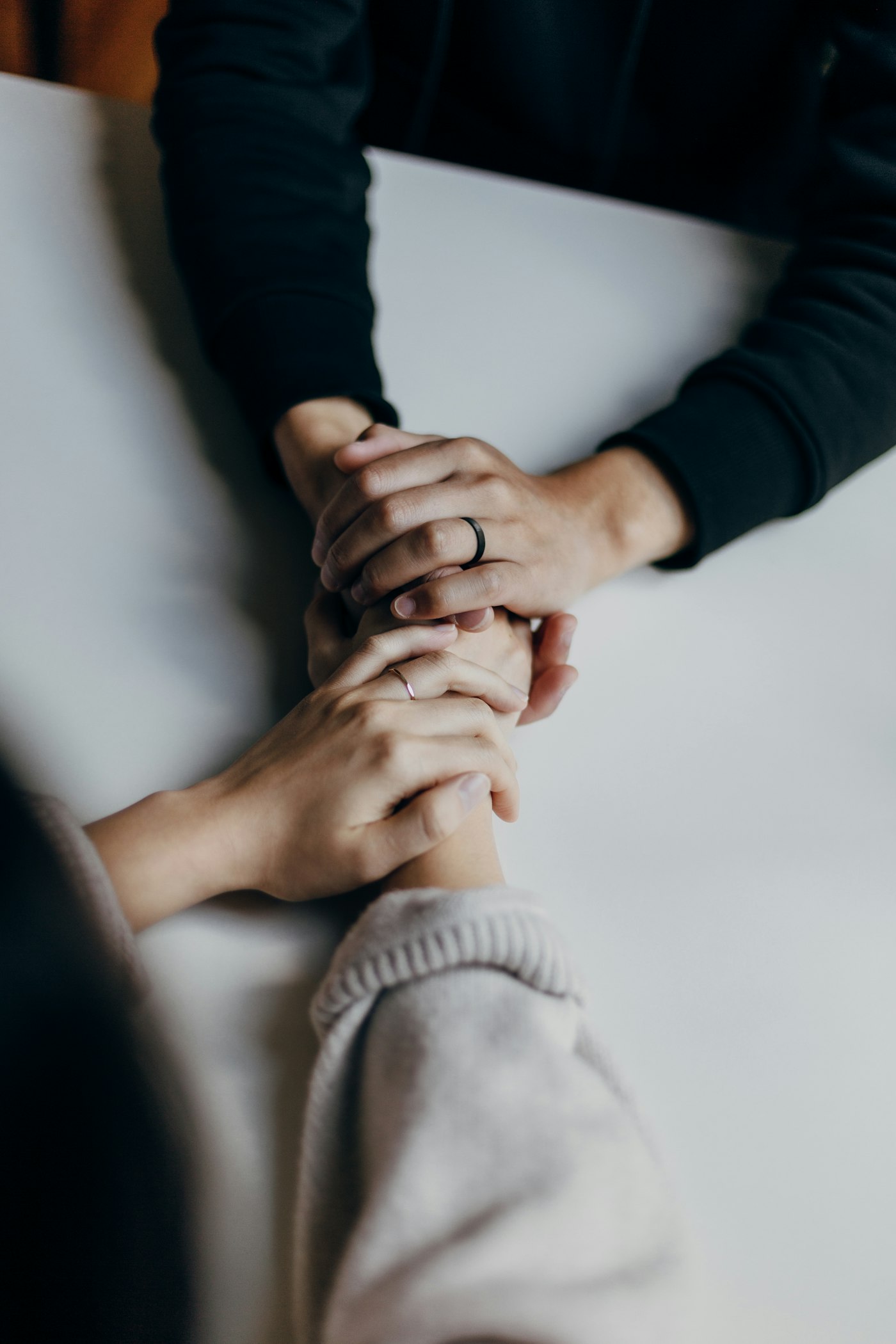Two people holding hands across a table — a moment of support.